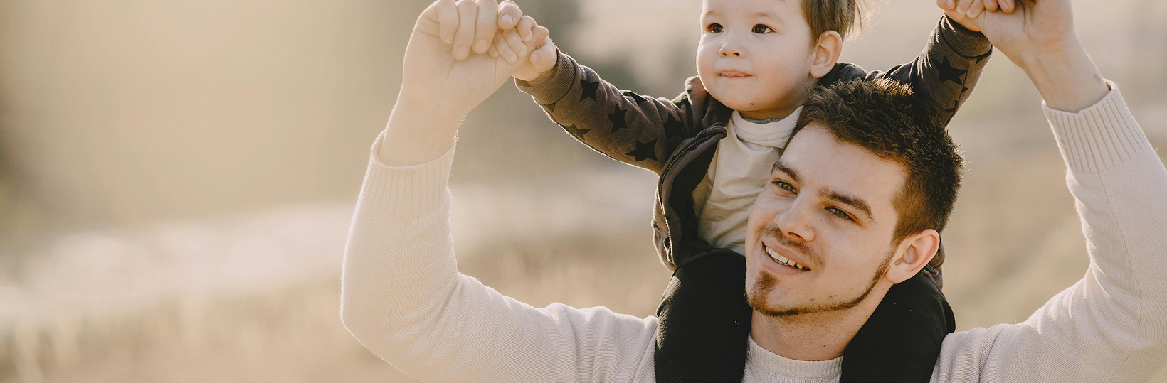Father walking outside with his child sitting on his shoulders